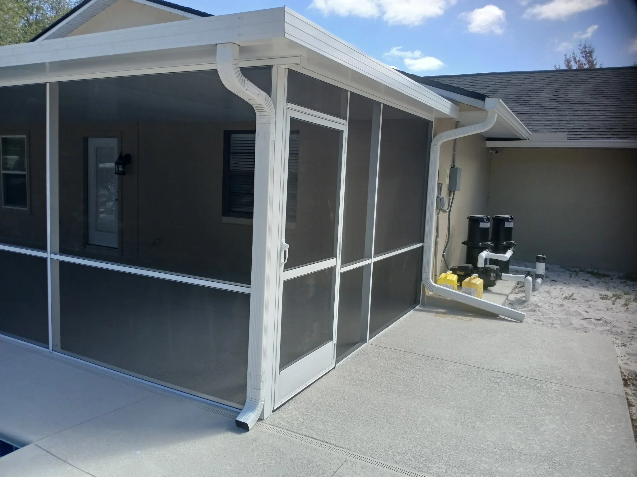 White aluminum screen enclosure with sliding doors and mesh panels attached to home
