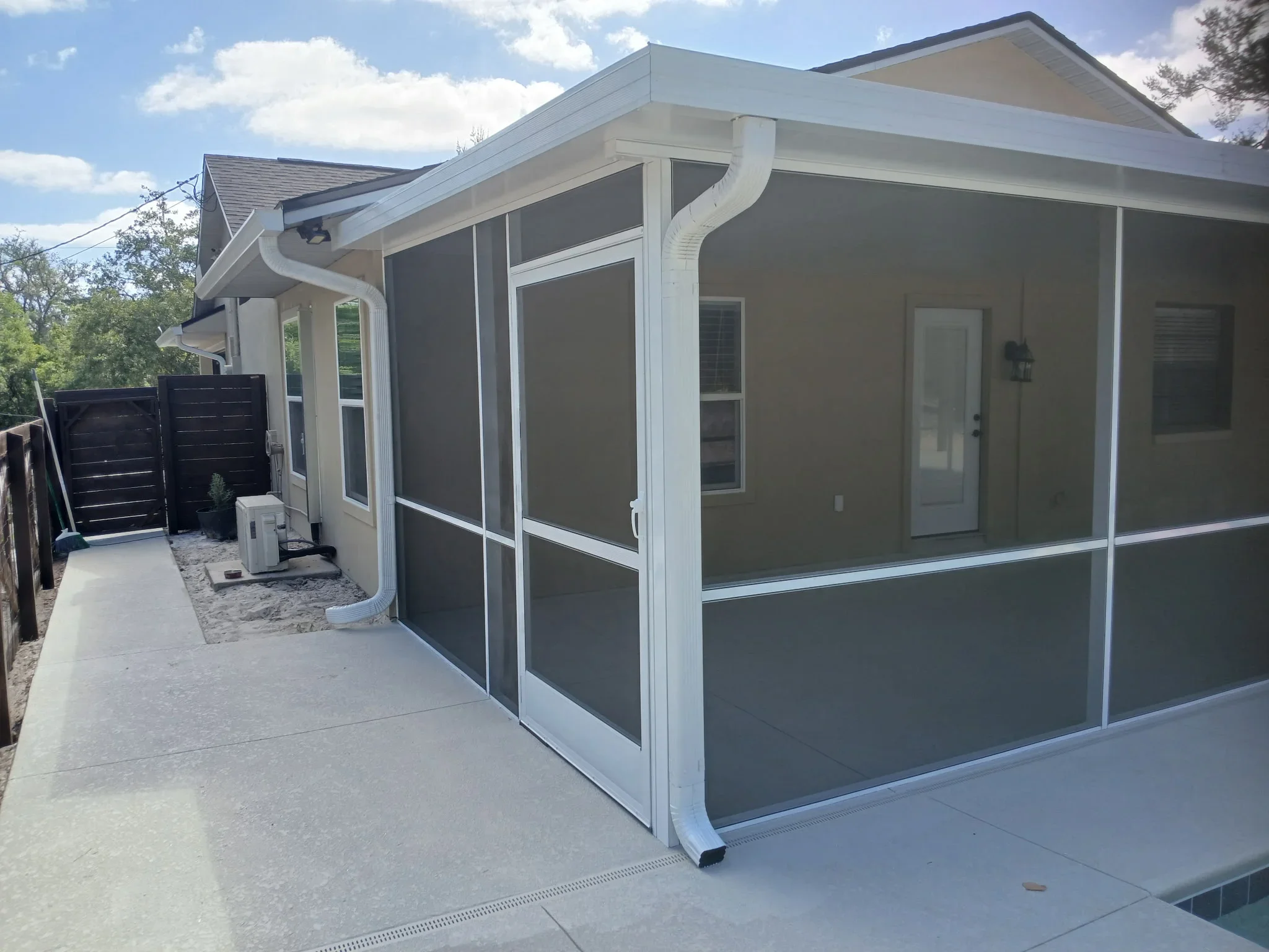 White aluminum screen porch with charcoal mesh panels and gable roof on concrete patio