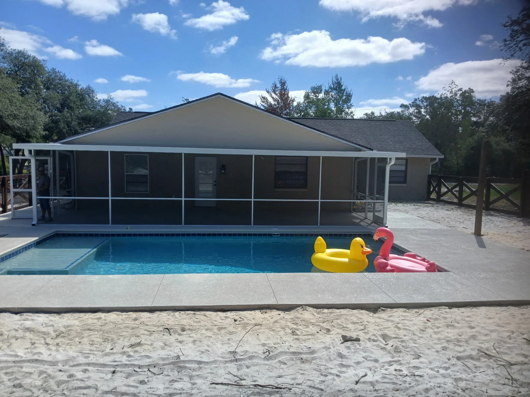 White aluminum pool enclosure with dark screens and gable roof over in-ground pool