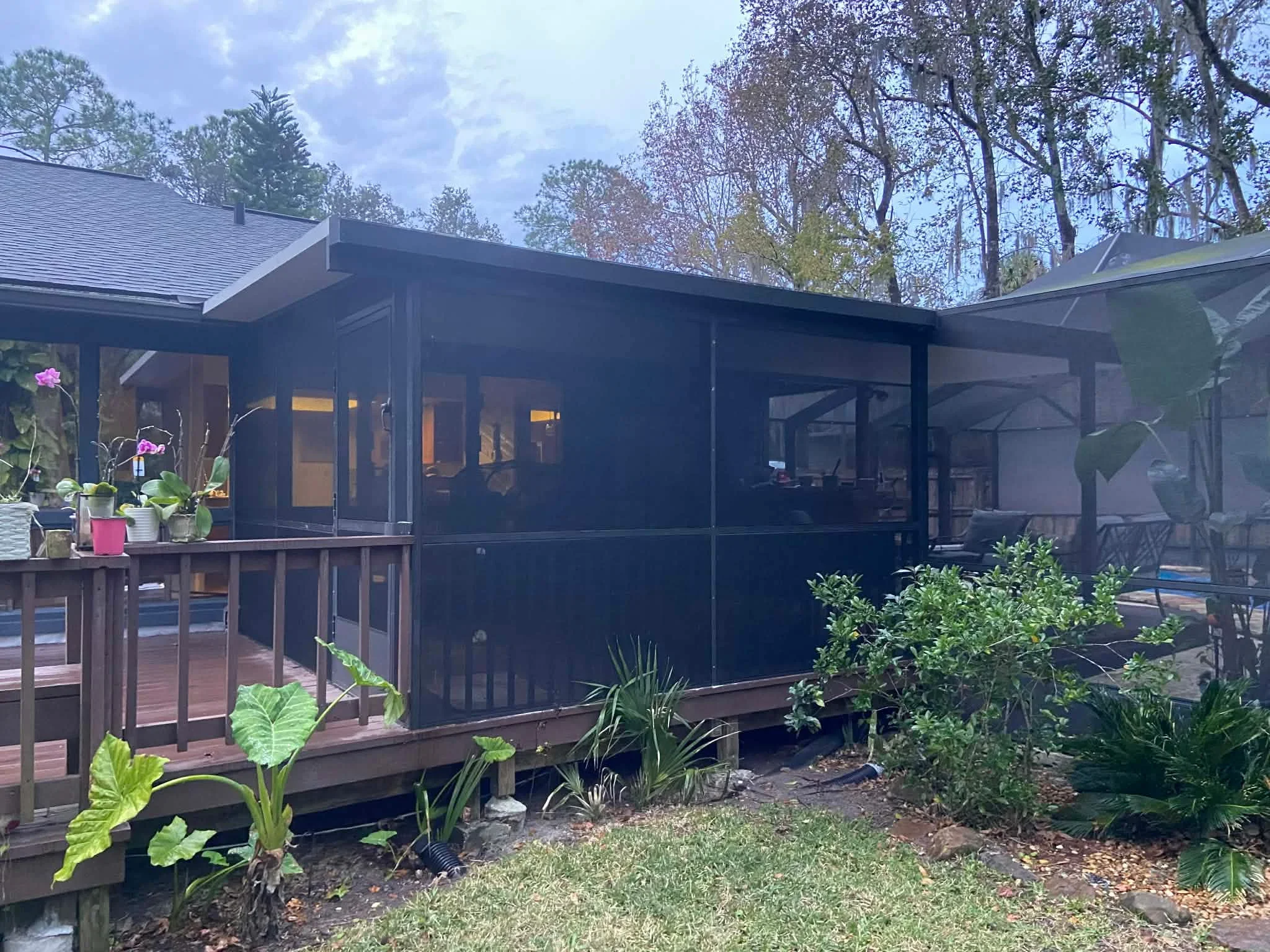 Black screen porch enclosure on composite deck with landscaping