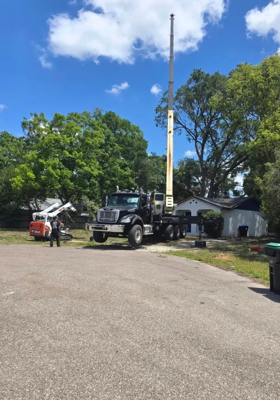 Crane truck removing large tree from residential Deltona property with crew and equipment