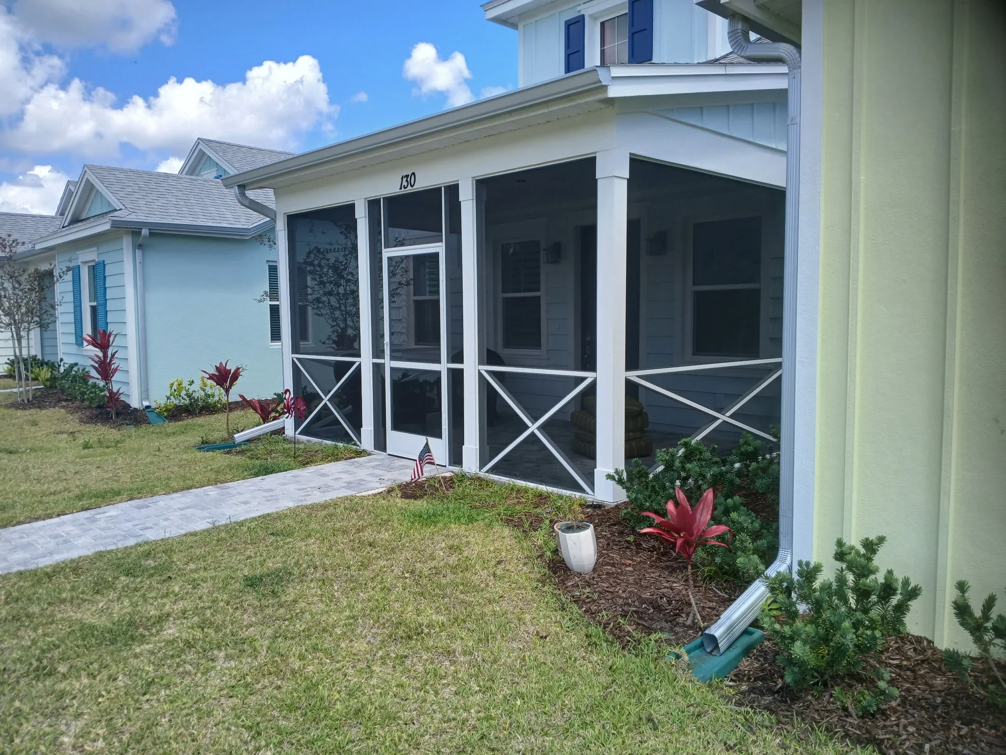 White screen porch enclosure with black screens and X-pattern detailing on residential home