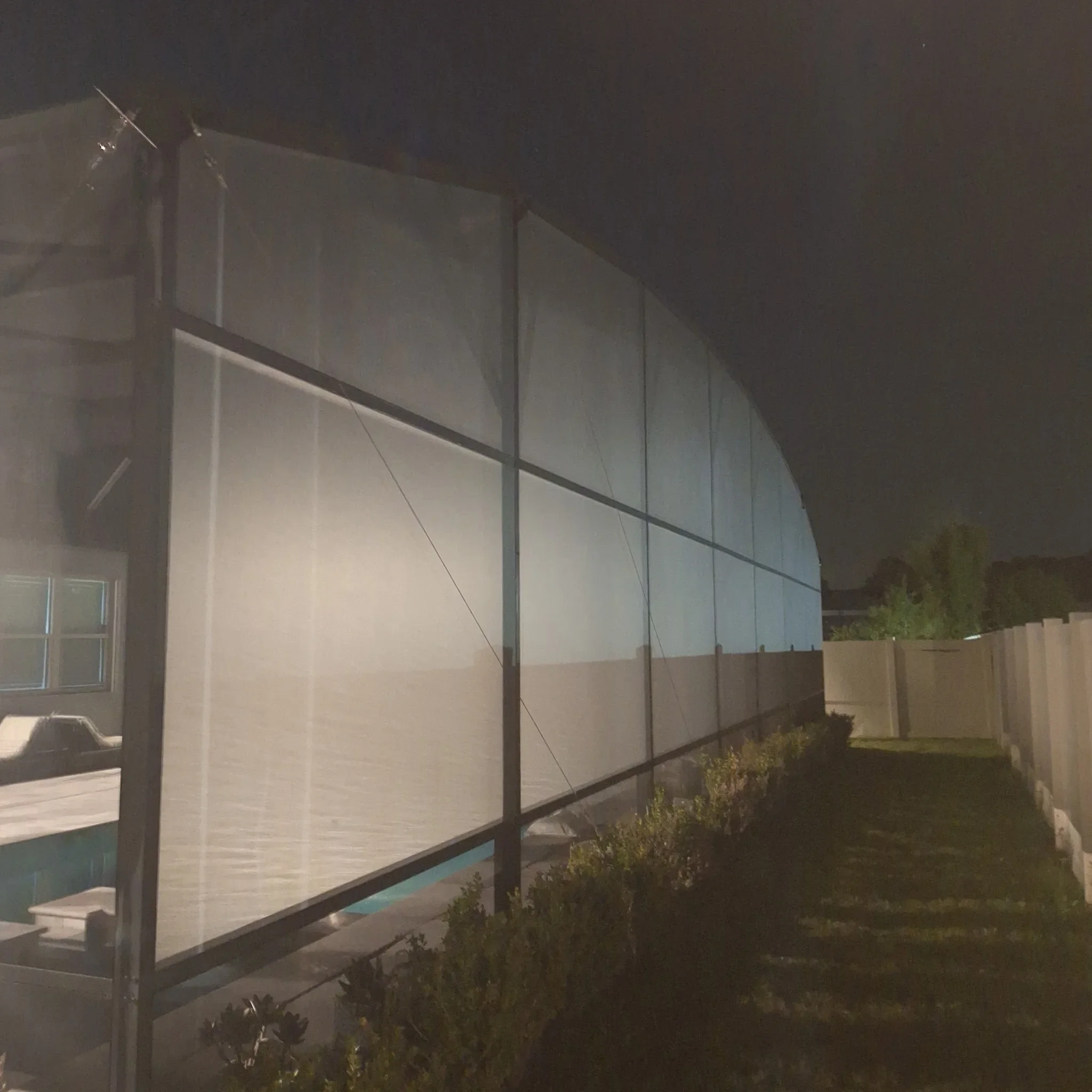 Illuminated screen enclosure with aluminum frame and translucent panels at night