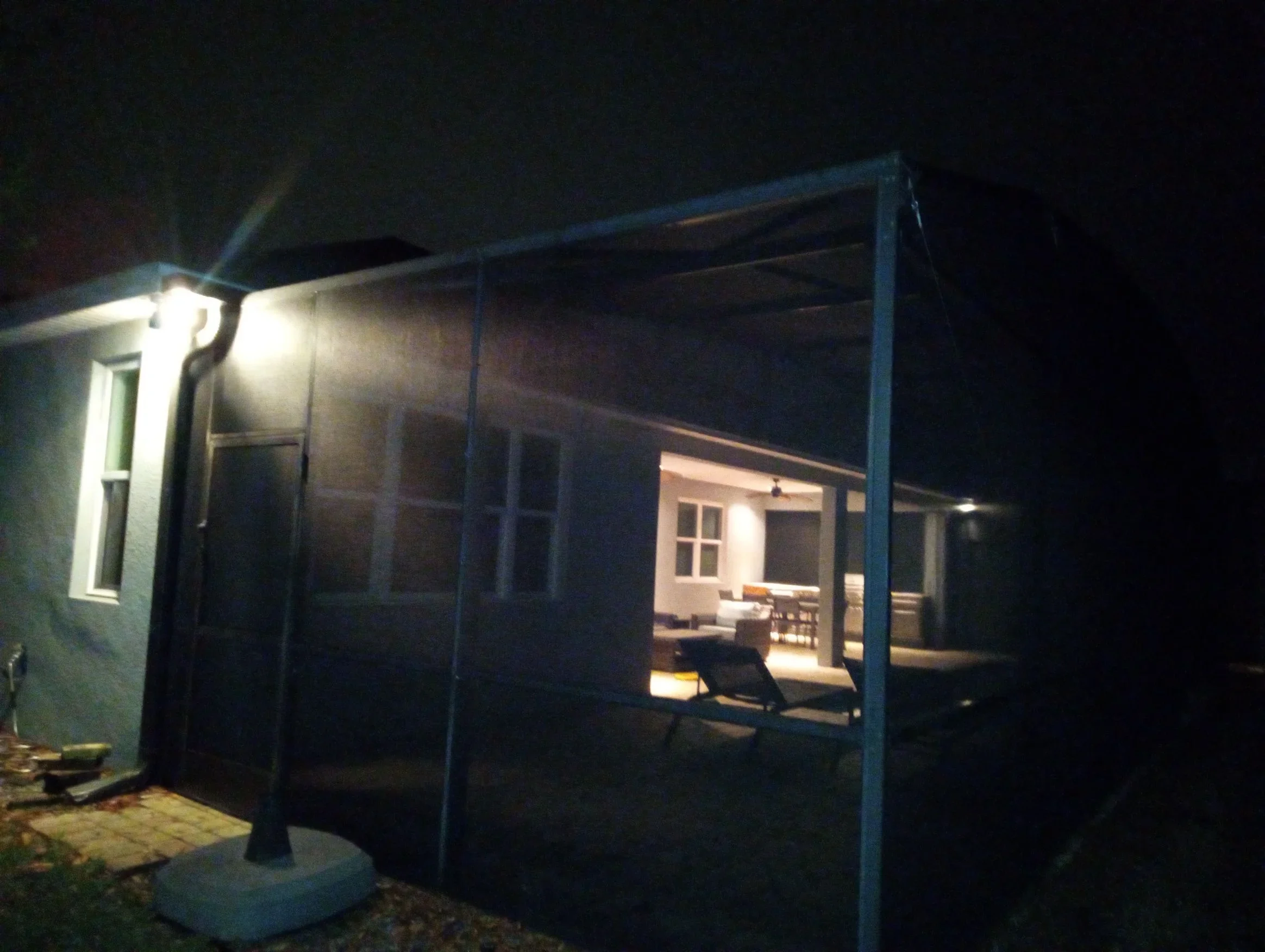Nighttime view of illuminated screen porch enclosure with aluminum frame and mesh screening