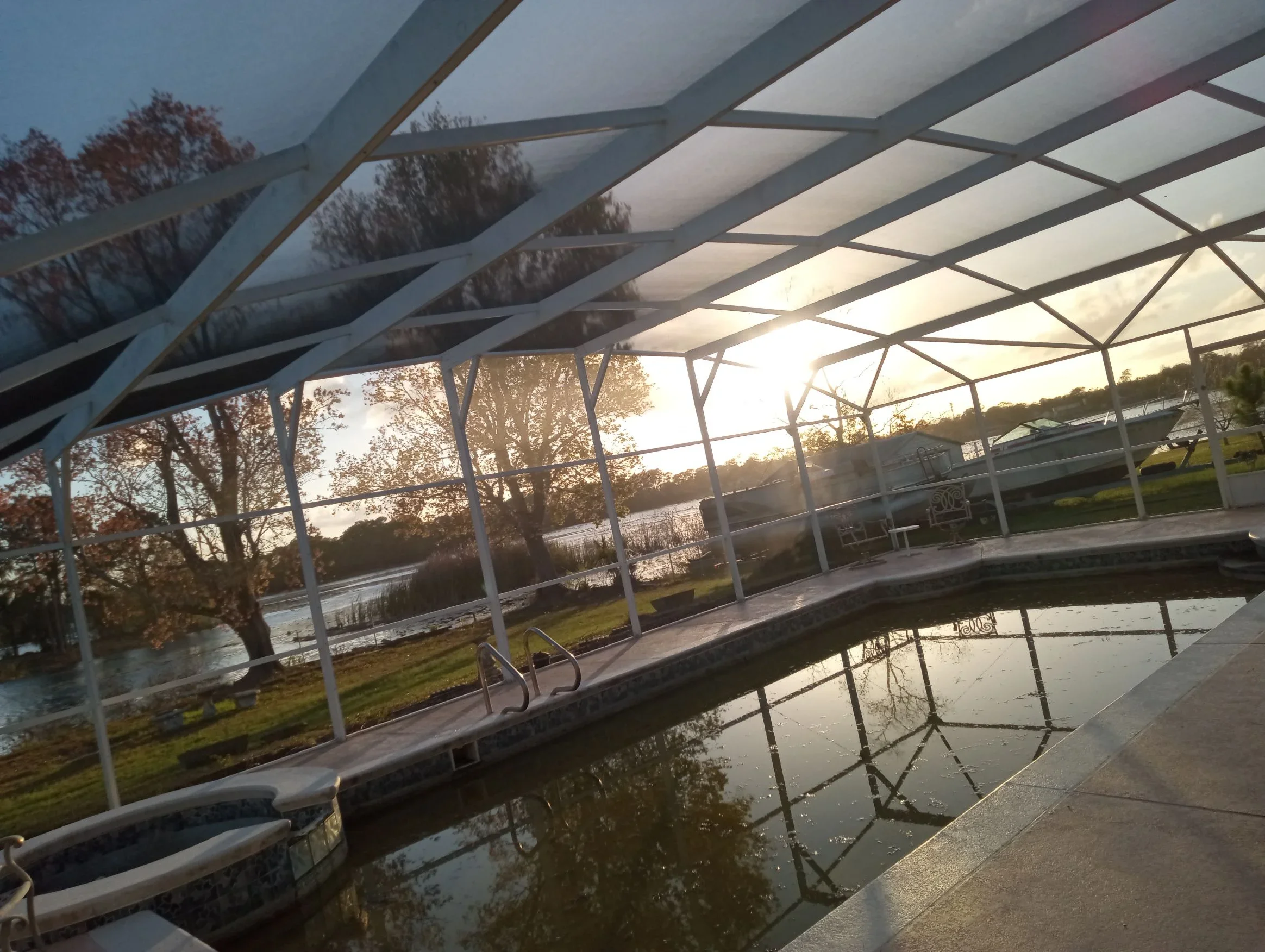 White aluminum pergola with polycarbonate panels over waterfront patio at sunset