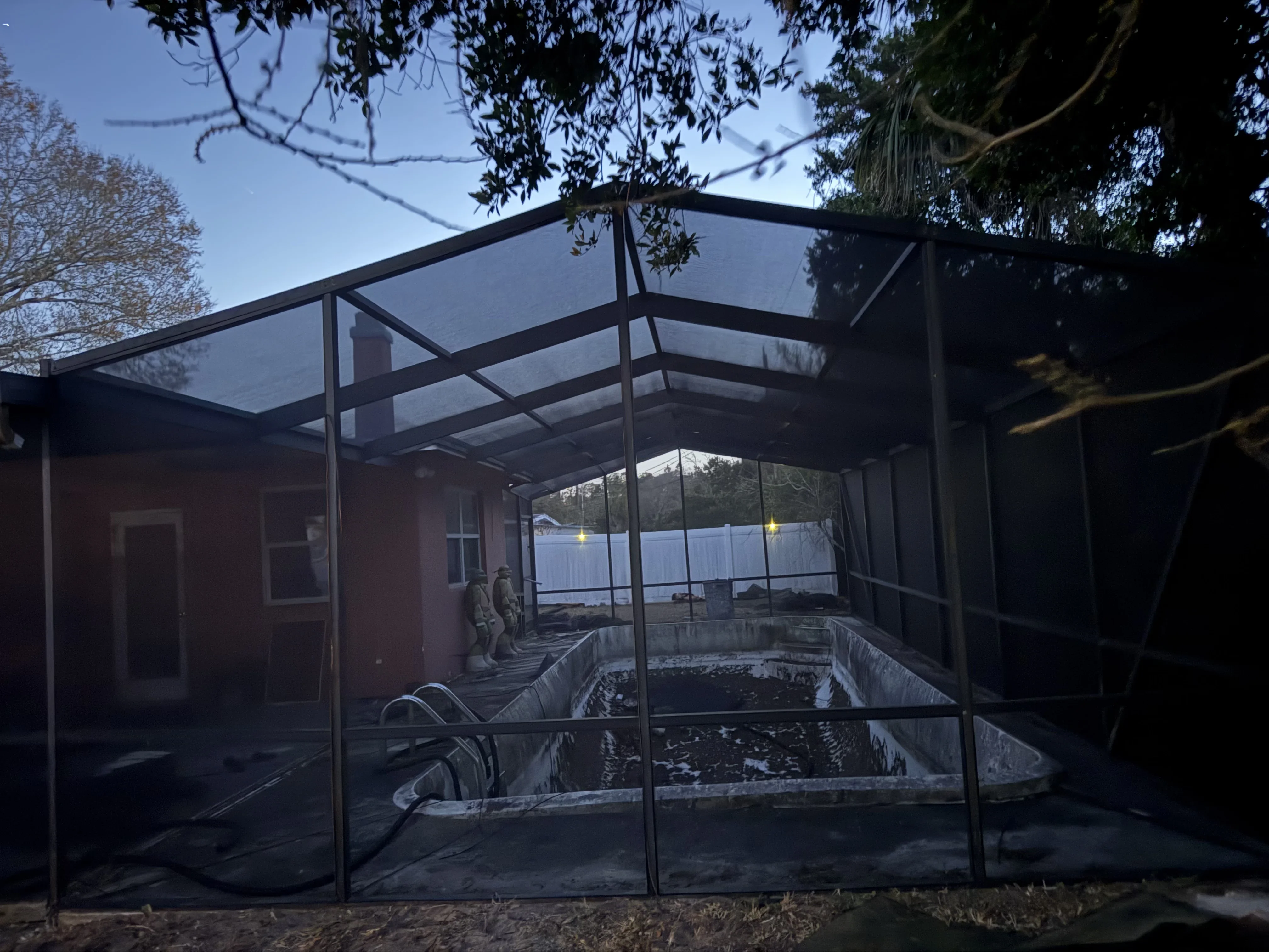 Black aluminum screen enclosure with polycarbonate roof over pool area overlooking water