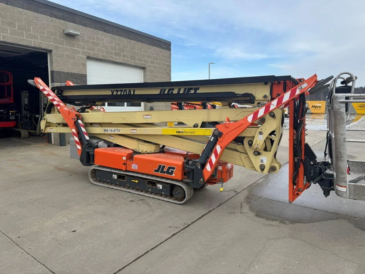 Two aerial lift machines with safety barriers positioned at equipment yard