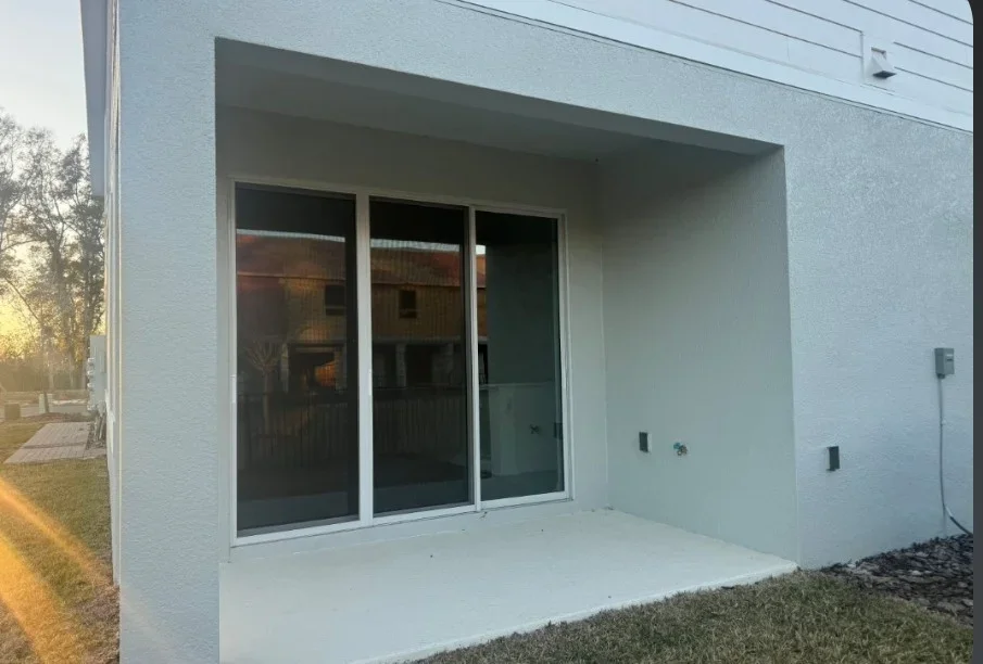 Modern white patio enclosure with three sliding glass doors and aluminum framing